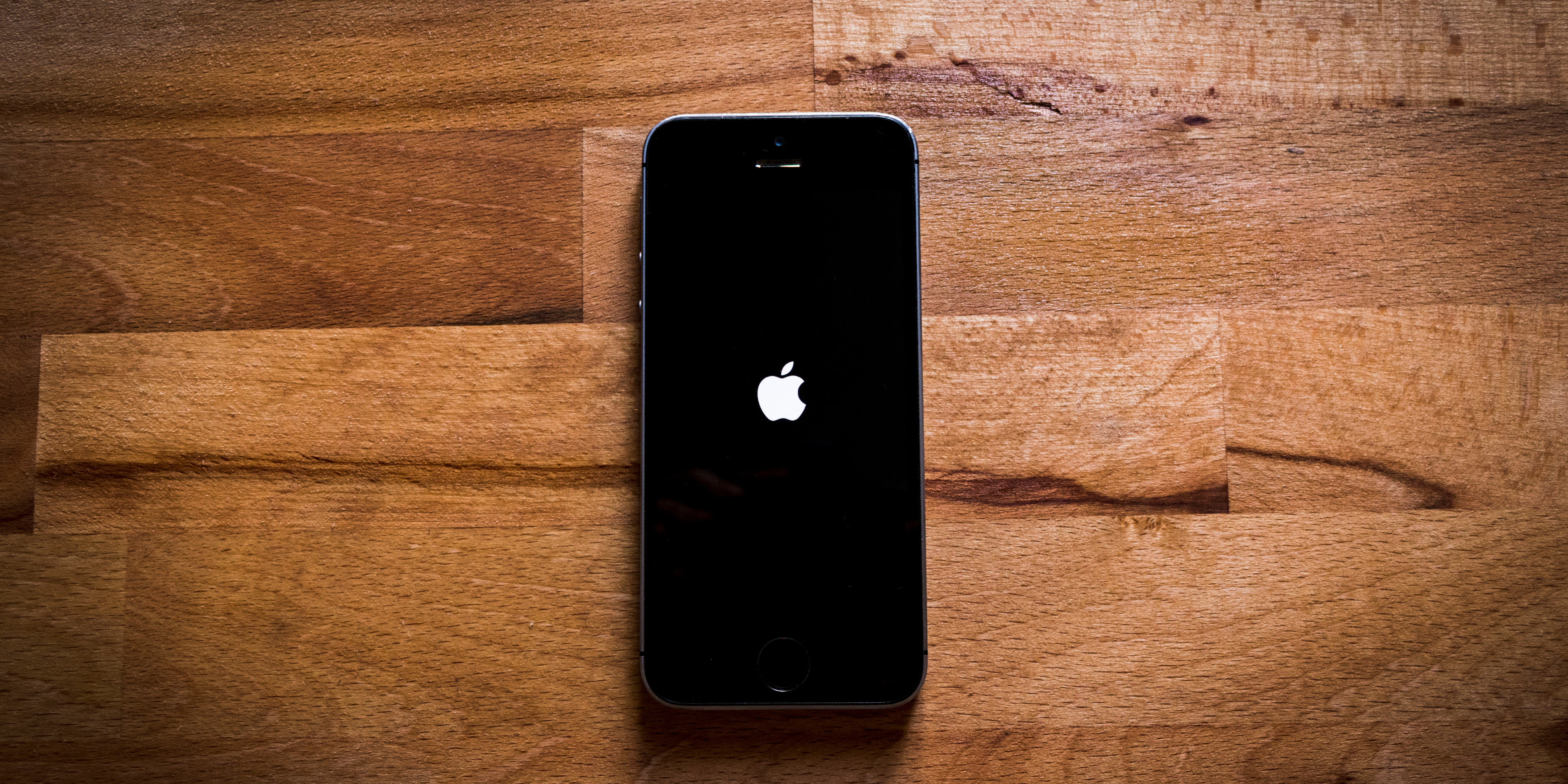 iPhone showing Apple logo stuck on screen with bold headline "iPhone Stuck on Apple Logo? 6 Fixes Before You Replace It" for Mobile Fix Experts blog.